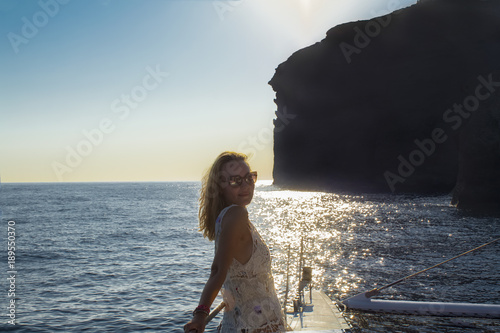 Woman traveling by boat at sunset among the islands. Summer Sntorini, Greece photo