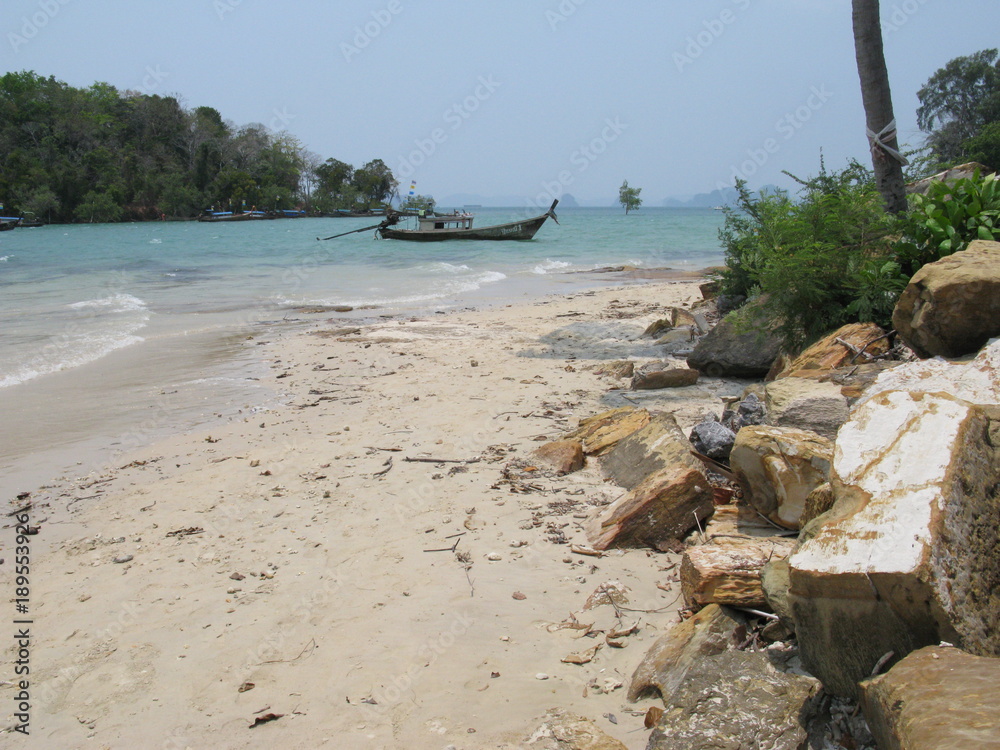 Naklejka premium krabi thailand beach with large rocks on it and a long tail boat in the water