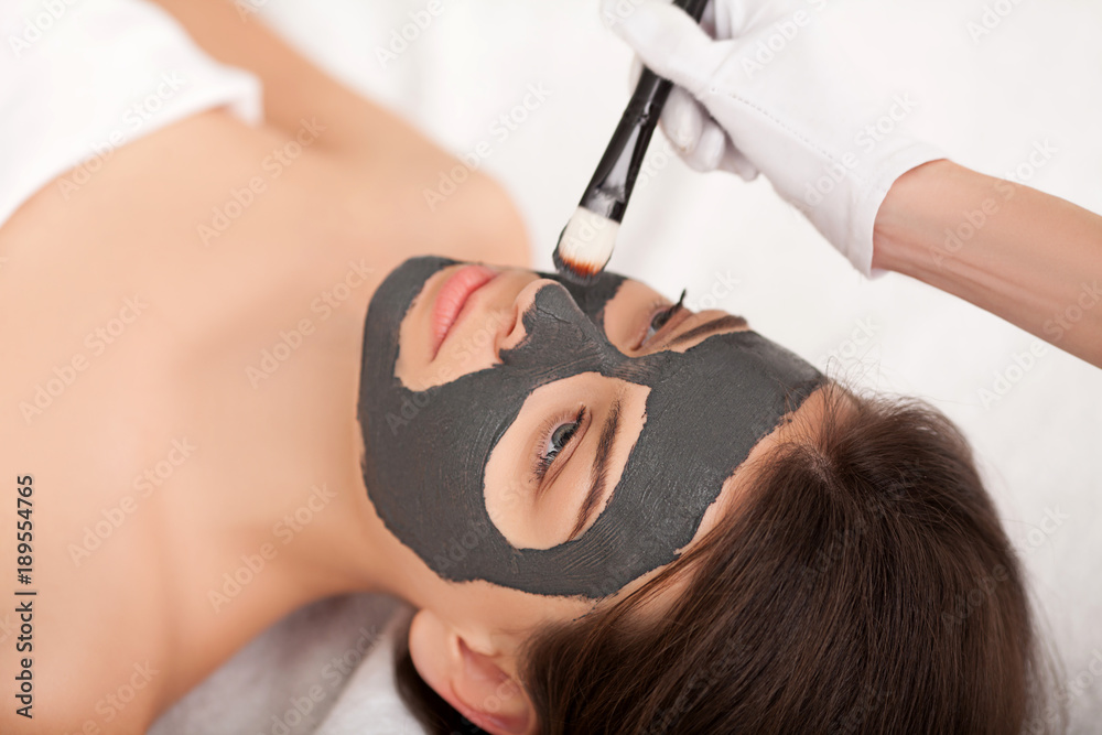 Naklejka premium Spa. Attractive funny woman with a clay mask on her face.