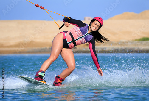 Wake boarding female sportsman beautiful girl with long black hair, sexy short wetsuit bikini, life style, recreation hobby fun, rider woman model posing on the seashore of the Red Sea
