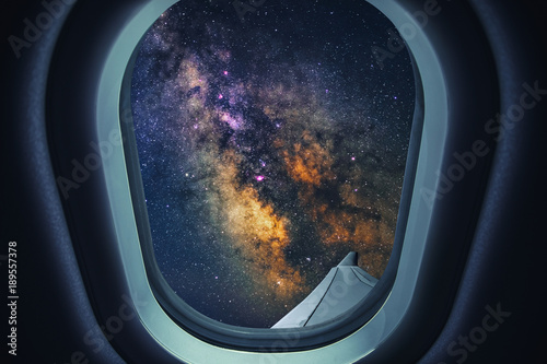 Airplane is flying at night. Space Milky Way view from plane window. Dark clear starry sky