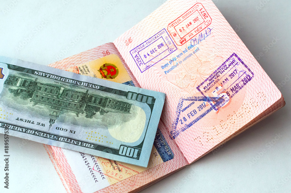 Fragment of Vietnamese visa sticker in a passport, immigration stamps in passport, 100 USD banknote Fragment of Vietnamese visa sticker in a passport, immigration stamps in passport, 100 USD banknote
