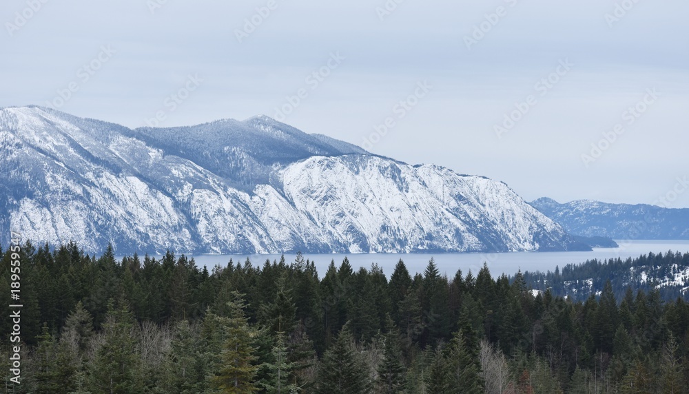 Snow covered mountain range, lake and trees Snow covered mountain range, lake and trees