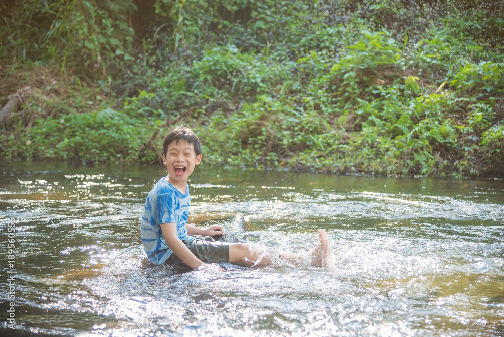 Fototapeta premium Young asian boy smiling while palying in the river