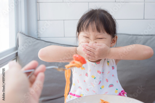 Little asian girl refuse toeat tomato in spagethi from her mother photo