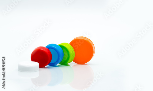 Macro shot detail of different size of white, green, red, blue and orange color round plastic screw caps on white background and copy space.