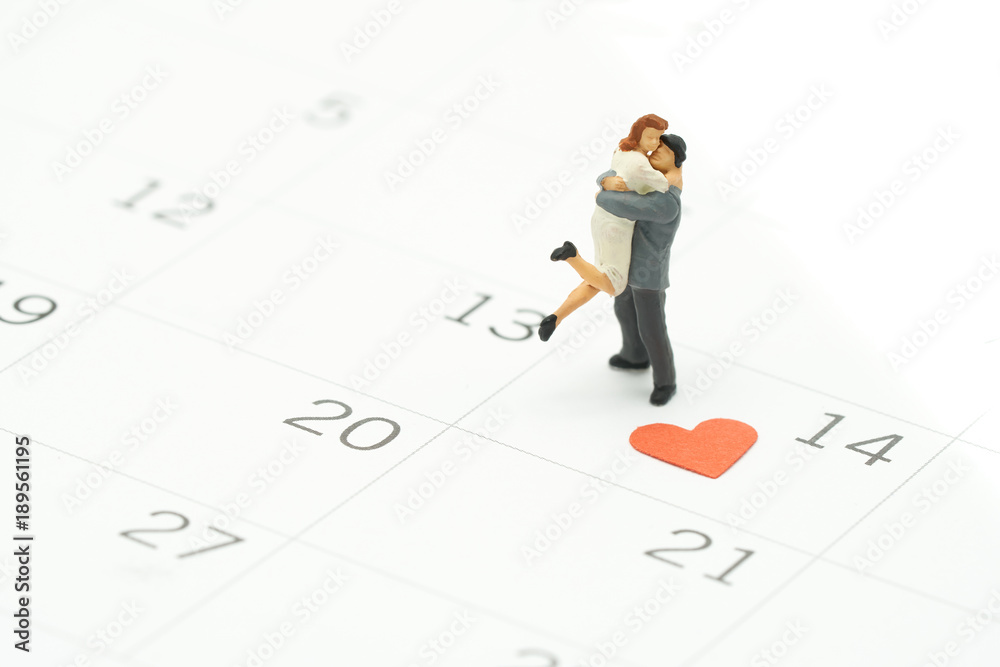Couple Miniature 2 people standing on Calendar. Day 14 meets Valentine Day with Heart shaped red paper. Red heart is the promise of love. using as background Valentine concept with copy spaces for you Couple Miniature 2 people standing on Calendar. Day 14 meets Valentine Day with Heart shaped red paper. Red heart is the promise of love. using as background Valentine concept with copy spaces for you