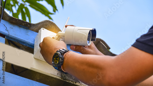 Technician installing CCTV camera system for security area.