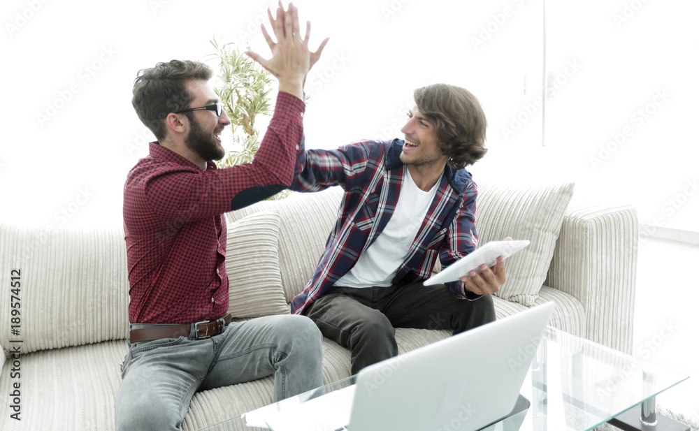Obraz premium wo guys sitting on the couch and giving each other five