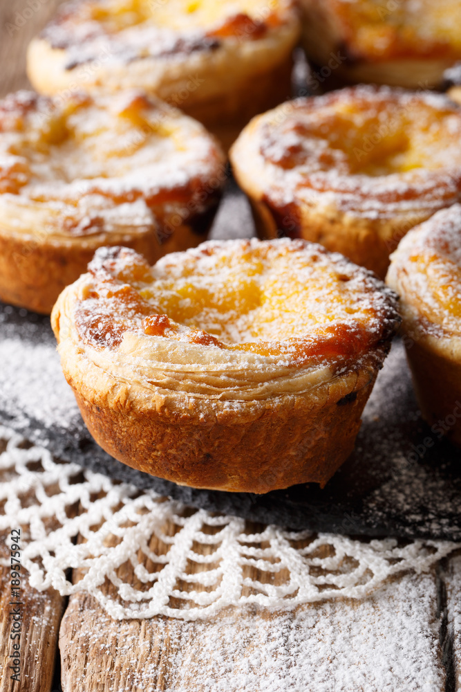 Freshly baked pastel de nata with powdered sugar close-up on the table. vertical