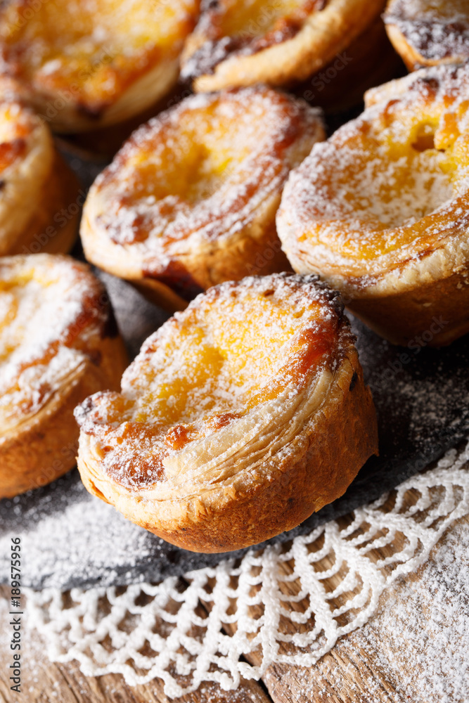 Portuguese dessert: Pastel de nata with powdered sugar close-up on the table. vertical