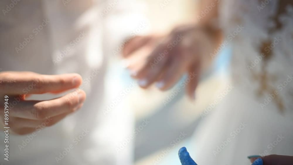 The groom takes an engagement ring that lies on a decorative jellyfish and puts the ring on the finger of his bride. A tropical wedding. Summer. The sun. Ocean. The groom takes an engagement ring that lies on a decorative jellyfish and puts the ring on the finger of his bride. A tropical wedding. Summer. The sun. Ocean.