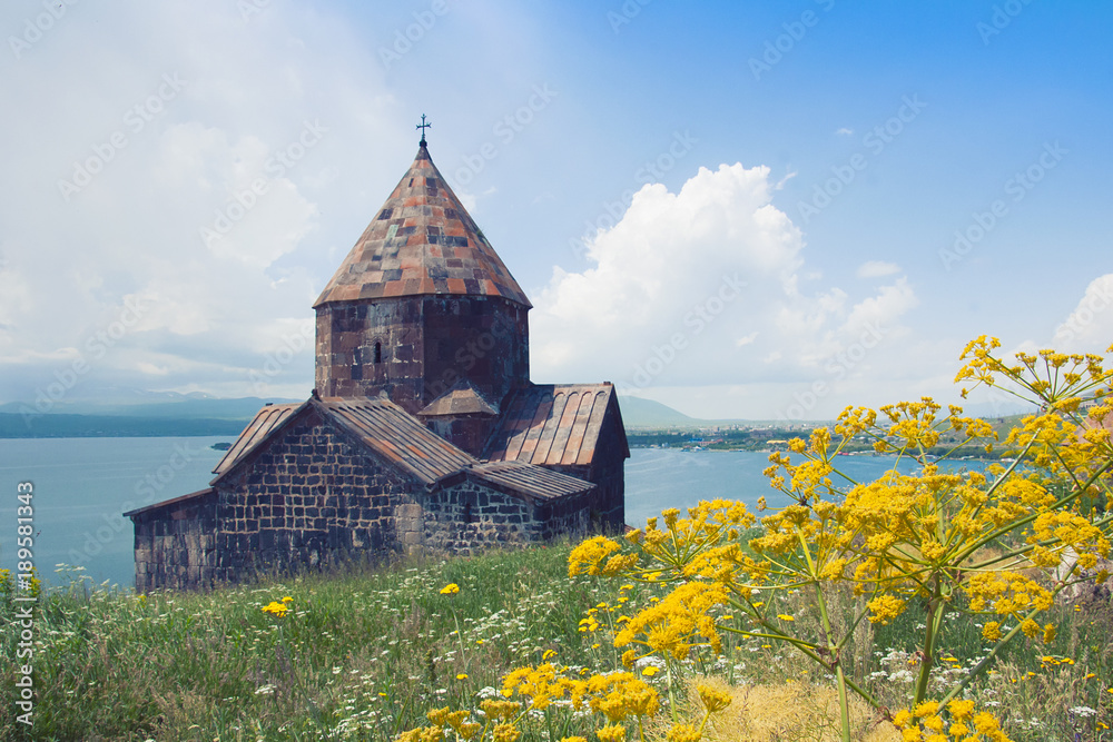 Sevanavank is a monastery on the shores of Lake Sevan, Gegharkunik province. The monastery was founded in 874. Sightseeing in Armenia. View of Lake Sevan, mountains, sky, meadow and yellow flowers.
