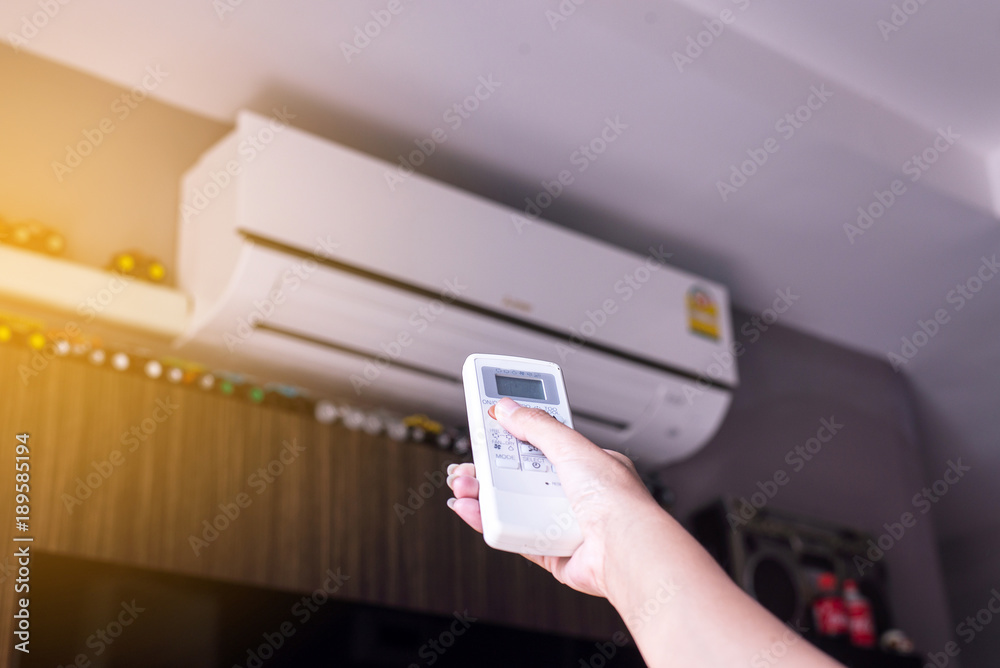 Hand using a remote control to activating air conditioning Hand using a remote control to activating air conditioning