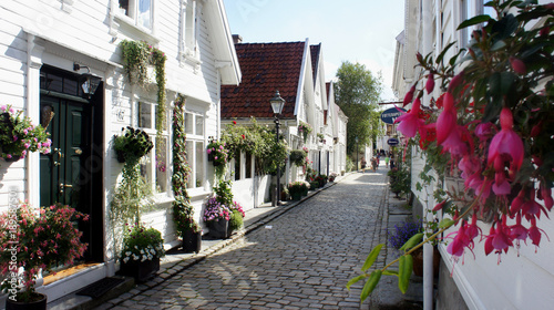 Street with flowers in pots and traditional white wooden houses in Gamle Stavanger in Rogaland, Norway, sunny day photo