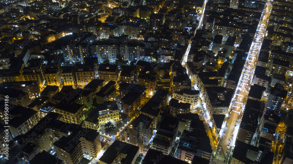 Aerial night view on the north part of the city of Naples, Italy. The streets are lit and surrounded by buildings and buildings.