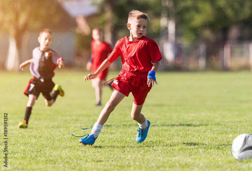 Boy kicking football on the sports field Boy kicking football on the sports field