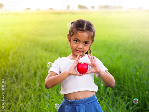 Portrait of little asian girl holding red heart.