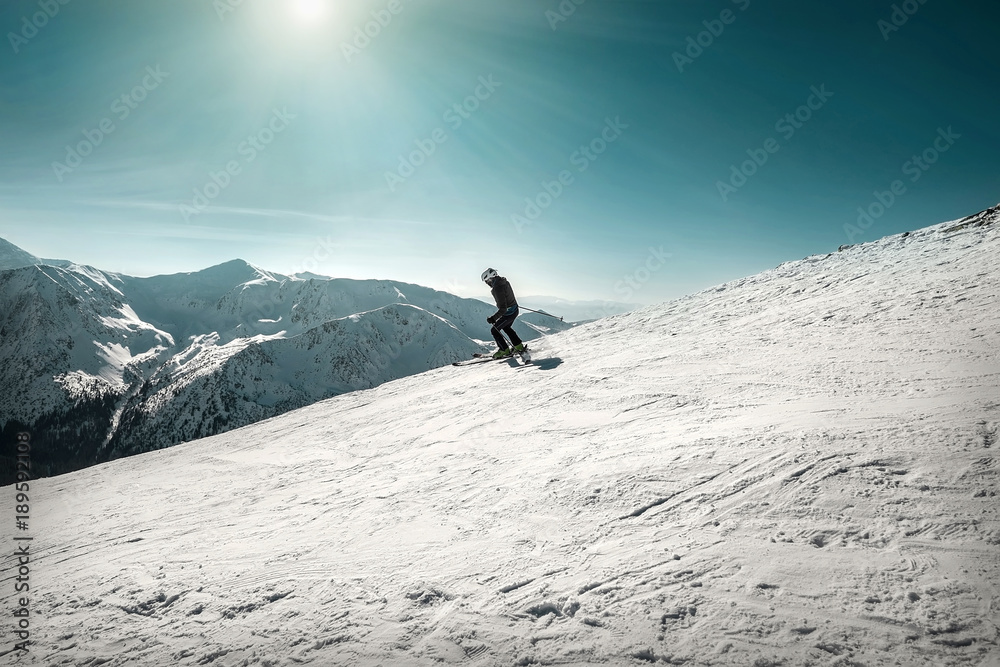 Nice mountains view at sunny day with skiers under blue sky with