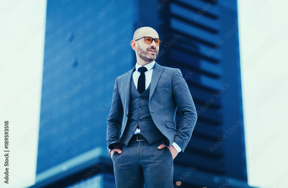 Fototapeta premium portrait of a successful young business man in a gray suit against the background of a business center