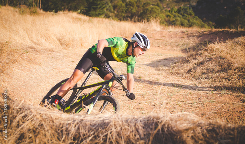 Wide angle view of a mountain biker speeding downhill on a mountain bike track in the woods