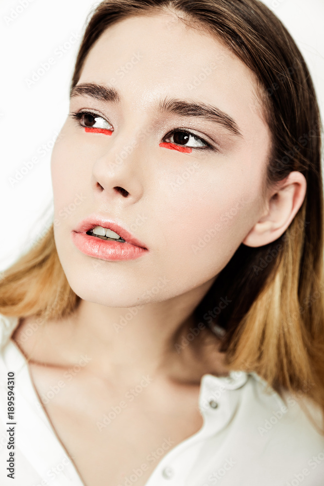 Portrait young beautiful serious dark-haired woman in white shirt on white background.