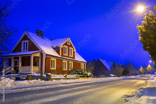 Winter scenery with red wooden house at night in Sweden photo