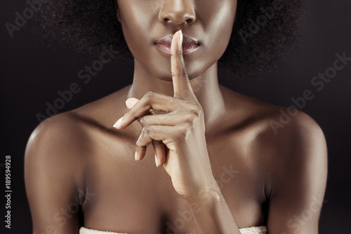 cropped shot of african american woman showing silence gesture isolated on black