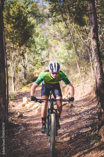 Wide angle view of a mountain biker speeding downhill on a mountain bike track in the woods