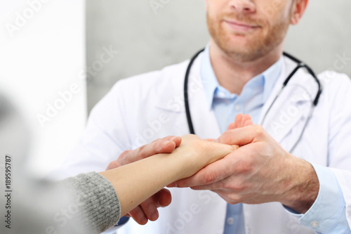 Wizyta u lekarza. Lekarz bada tętno pacjenta trzymając go za nadgarstek.