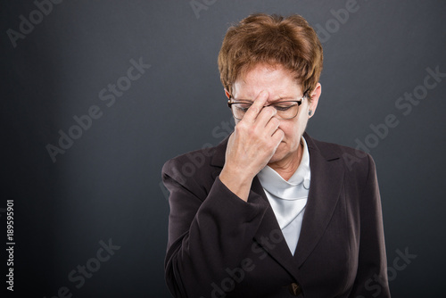 Business senior lady holding head like concentrating