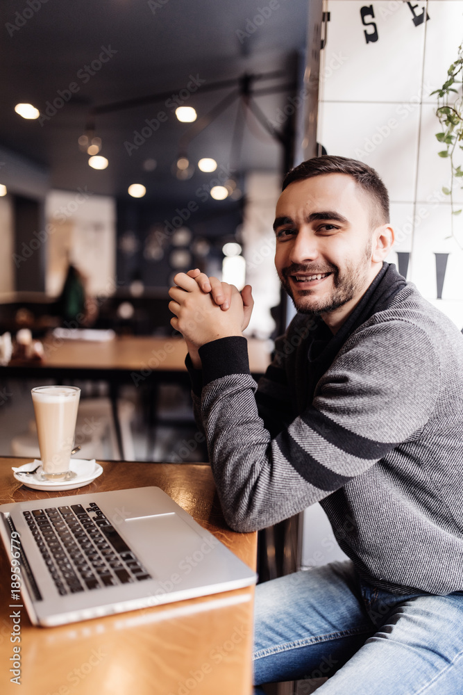 Handsome bearded man drinking coffee while working in a cafe Handsome bearded man drinking coffee while working in a cafe