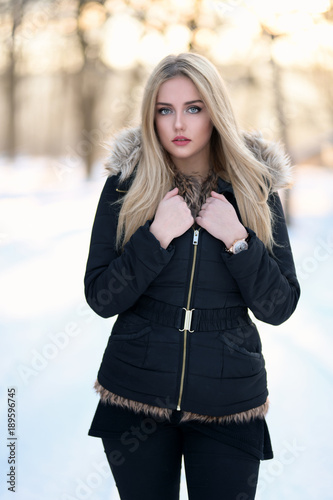 Portrait of a young blond woman with long healthy hair in winter park.