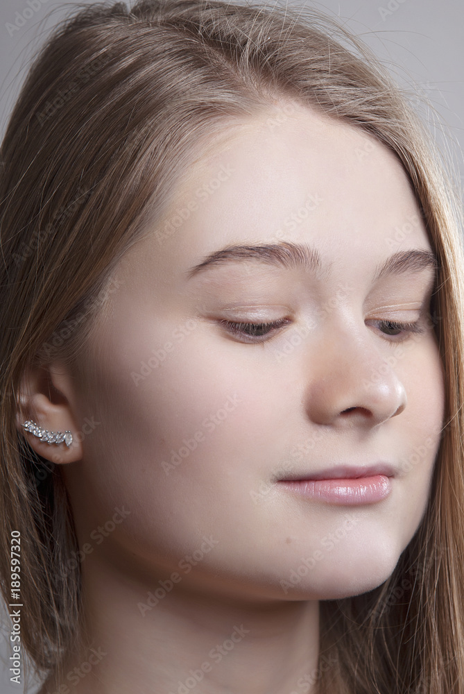 Portrait of a young girl with Nude make-up on closed eyes on gray isolated background close-up Portrait of a young girl with Nude make-up on closed eyes on gray isolated background close-up