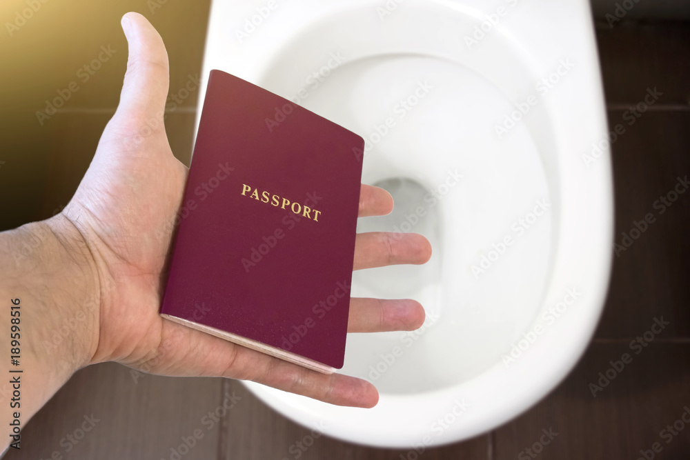 Hand holds the citizen's passport over the toilet, throw out his