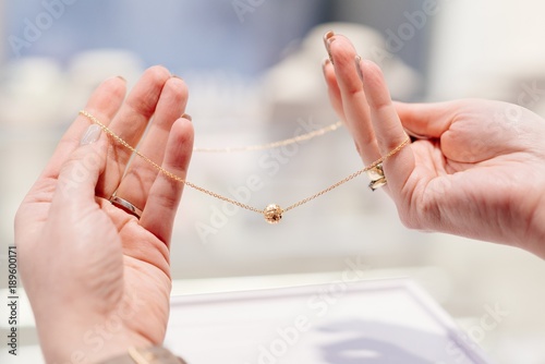 Woman owner of jewelry shop presenting gold necklace.