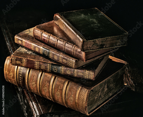 Old books stack in directional dark light.