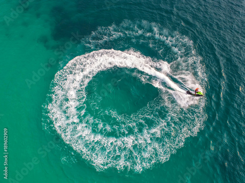 People are playing a jet ski in the sea.Aerial view. Top view.amazing nature background.The color of the water and beautifully bright. Fresh freedom. Adventure day.clear turquoise at tropical beach. © MAGNIFIER