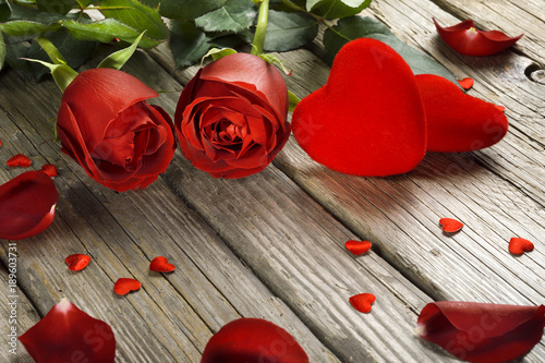 Valentine's Day background, roses and velvet hearts on old wooden table
