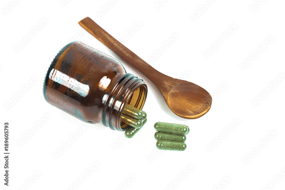 Herbal medicine capsules spilling out of a bottle on white Herbal medicine capsules spilling out of a bottle on white