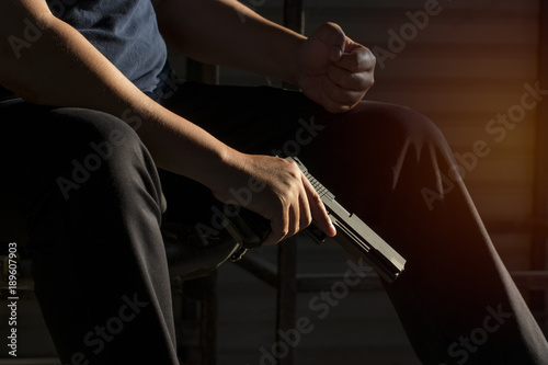 Close up, Hand of a man carrying a magazines gun. There is a bullet in the chamber. Prepare to used protect yourself. He dodged in a dark room with sunlight. Blur and soft focus. 