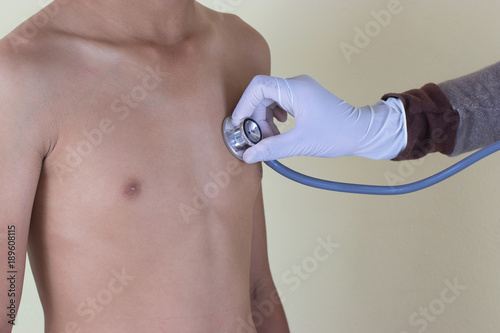 The doctor uses a stethoscope to listen to the boy's heartbeat. He is sick with heart disease and treated in a clinic. Healthcare and Medical concept.