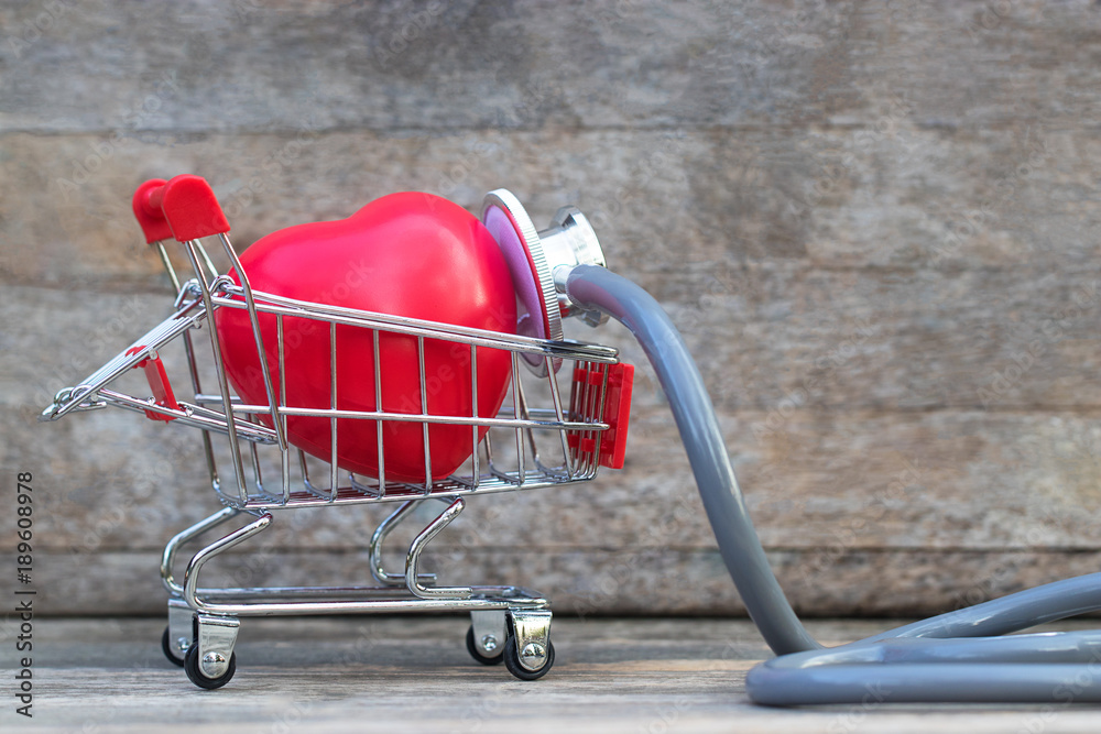 Φωτογραφία Red heart shape in shopping cart on table and wooden background