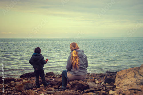 mother and her child looking the sea, two people are waiting for someone to come from far away