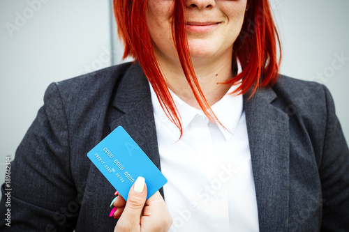 Concept of purchases, banking services. A woman in a suit and glasses shows a credit card. With a place for advertising text. photo