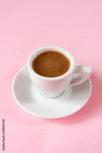  A cup of espresso with foam in a white cup on a white saucer on a vivid pink background. Place for text. Close up. 