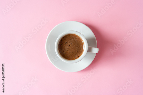  A cup of espresso with foam in a white cup on a white saucer on a vivid pink background. Place for text. Flat lay