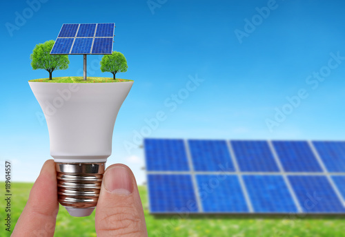 Eco LED light bulb with solar panels in hand. Concept of green energy.