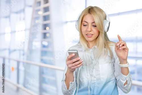 Happy young blonde woman listening to music
