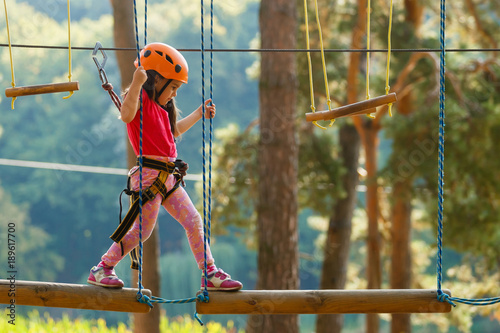 Portrait of cute little boy and girl walk on a rope bridge in an adventure rope park. photo